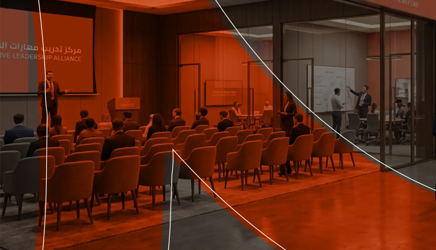 A Sarat Academy seminar hall in coral and walnut, with a trainer presenting to a full room